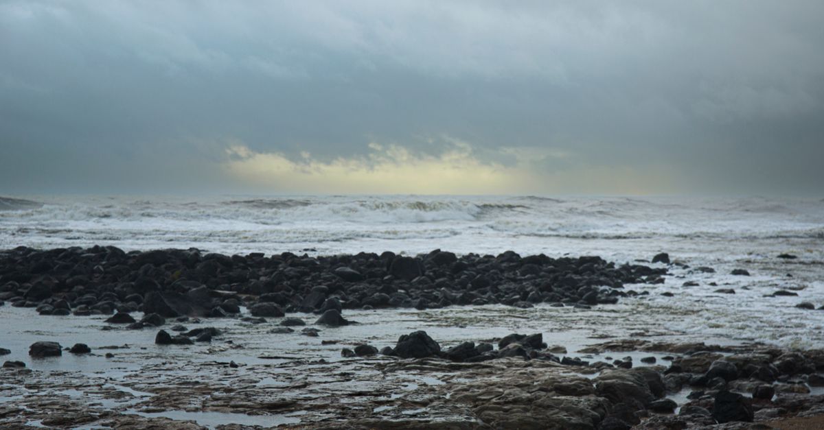 Littoral rocheux battu par les vagues sous un ciel de tempête