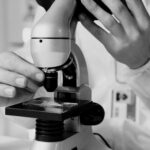 A scientist in a lab coat using a microscope for research in a laboratory setting.