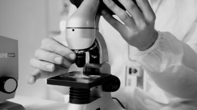 A scientist in a lab coat using a microscope for research in a laboratory setting.